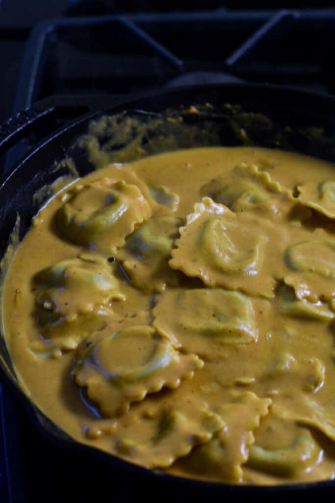 Pumpkin pasta sauce with ravioli, in a black skillet