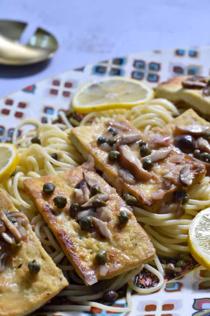 Easy Tofu Piccata [with lemon and capers] on a platter of spaghetti