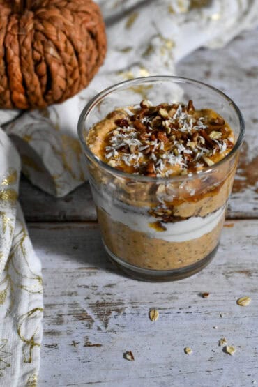 Pumpkin Pie Overnight Oats on a table with a decorative napkin and pumpkin in the background