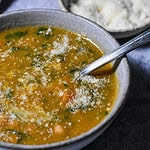 Creamy Lemon Chickpea Potato Soup in a bowl with a bowl of parmesan behind it.