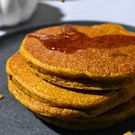 Stack of Healthy Pumpkin Pancakes with a drizzle of maple syrup