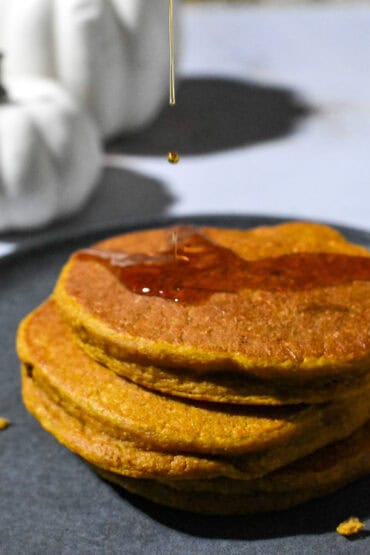 Stack of Healthy Pumpkin Pancakes with a drizzle of maple syrup