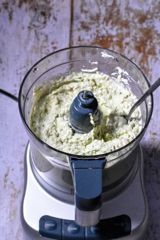 Creamy cheese, bean, and spinach mixture in a food processor
