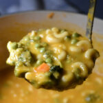 Broccoli Cheddar Soup with Noodle in a ladle.