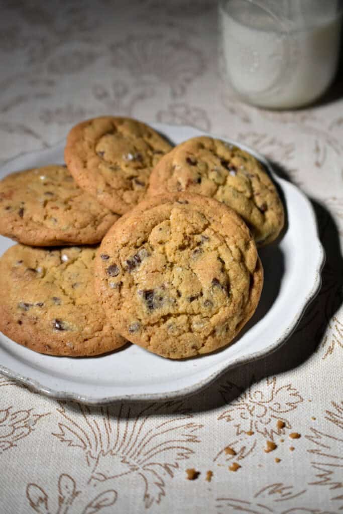 Bread Flour Chocolate Chip Cookies on a plate with a glass of milk in the back