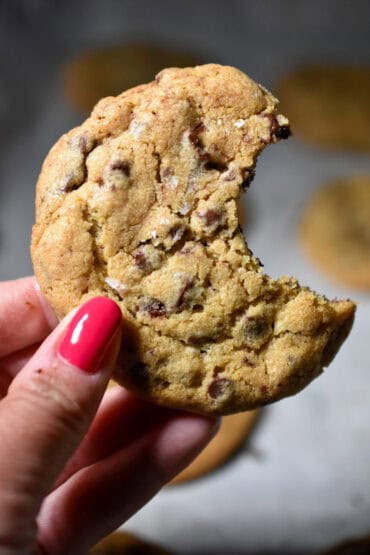 Bread Flour Chocolate Chip Cookie with a bite taken out of it, being help up.