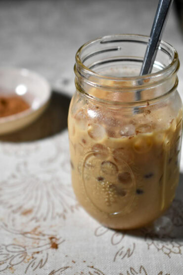 Pumpkin Iced Latte in a mason jar with a bowl of spices in teh background