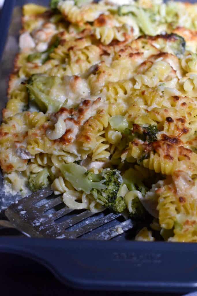Lighter Chicken Broccoli Bake in a pan, being served with a silver spatula