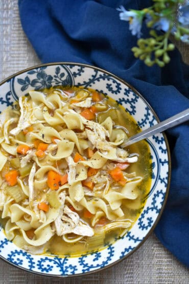 Homemade chicken noodle soup with shredded chicken, carrots, celery and egg noodles topped with freshly cracked black pepper.
