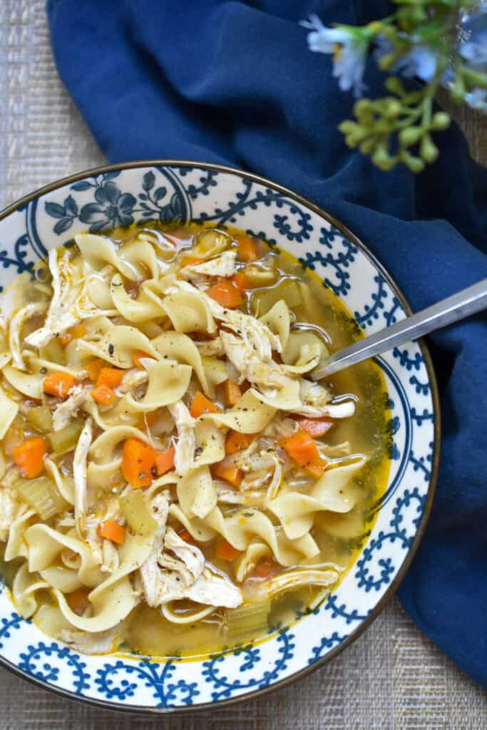 Homemade chicken noodle soup with shredded chicken, carrots, celery and egg noodles topped with freshly cracked black pepper.