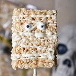 Homemade mummy Rice Krispie treats decorated with white chocolate bandages and candy eyes for Halloween