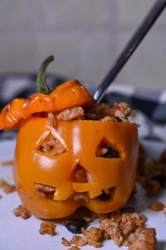 Halloween stuffed peppers carved into jack-o’-lanterns and filled with ground turkey, rice, black beans, and cheese