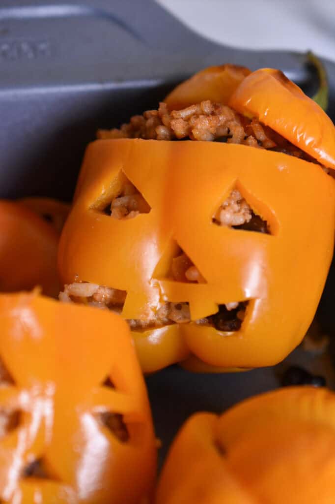 Halloween stuffed peppers carved into jack-o’-lanterns and filled with ground turkey, rice, black beans, and cheese. In a pan